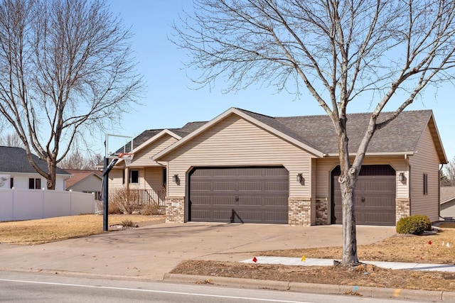 view of front facade with brick siding, an attached garage, concrete driveway, and fence