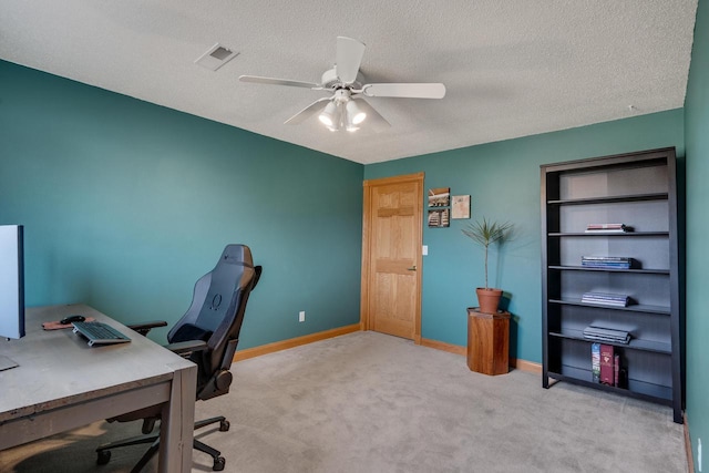 carpeted office space featuring ceiling fan, baseboards, visible vents, and a textured ceiling