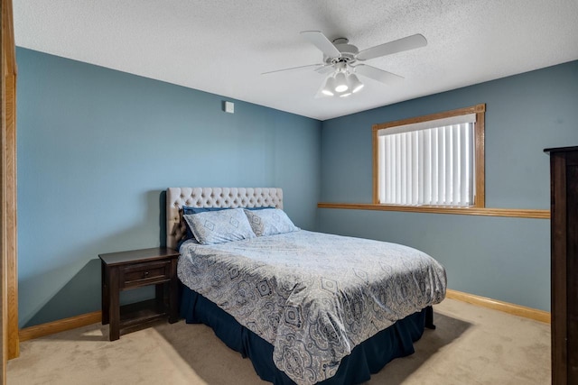 carpeted bedroom featuring baseboards, a textured ceiling, and a ceiling fan