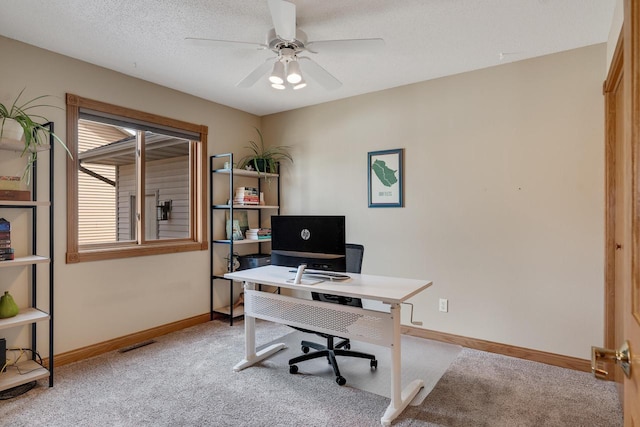 home office with light colored carpet, a textured ceiling, baseboards, and ceiling fan