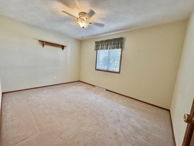 empty room featuring visible vents, light carpet, a ceiling fan, a textured ceiling, and baseboards