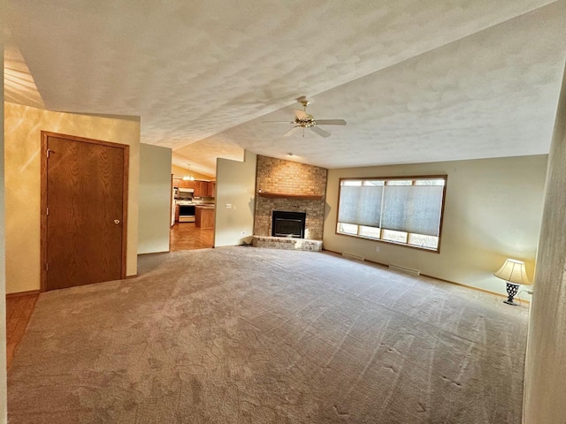 unfurnished living room featuring baseboards, a fireplace, ceiling fan, a textured ceiling, and carpet flooring