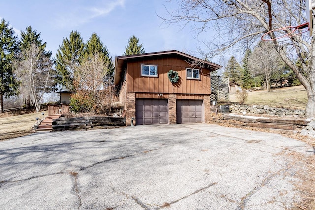 view of home's exterior with a garage, brick siding, and driveway