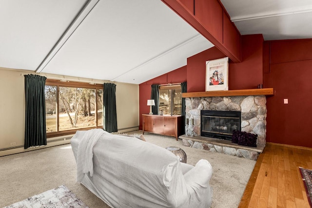 bedroom with a stone fireplace, lofted ceiling, wood finished floors, and a baseboard heating unit