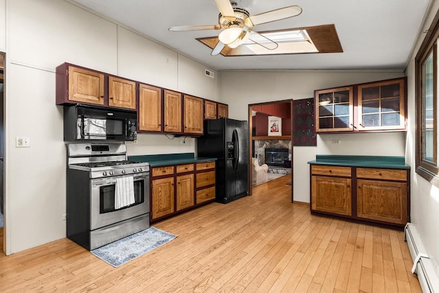 kitchen featuring lofted ceiling, baseboard heating, black appliances, and brown cabinets