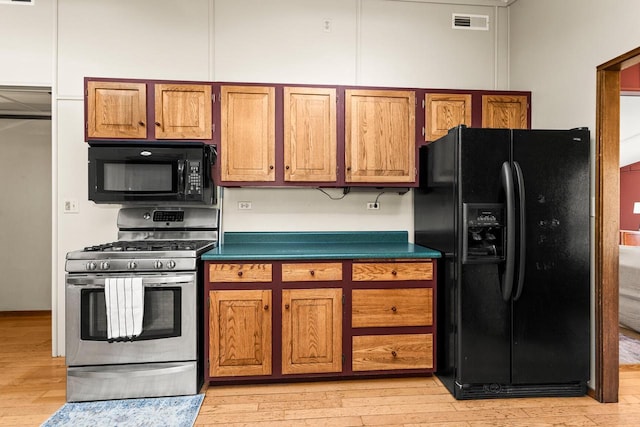 kitchen with brown cabinetry, black appliances, and light wood-type flooring