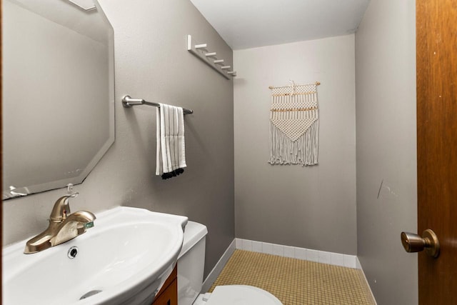 half bath featuring baseboards, toilet, and vanity