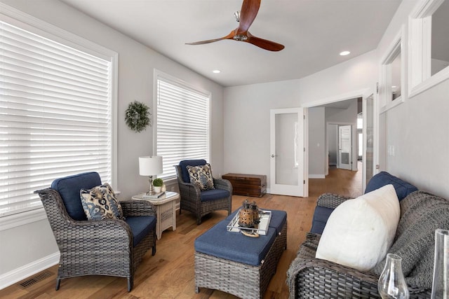 living room with baseboards, visible vents, light wood finished floors, and ceiling fan