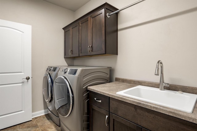 laundry room with washing machine and dryer, cabinet space, baseboards, and a sink