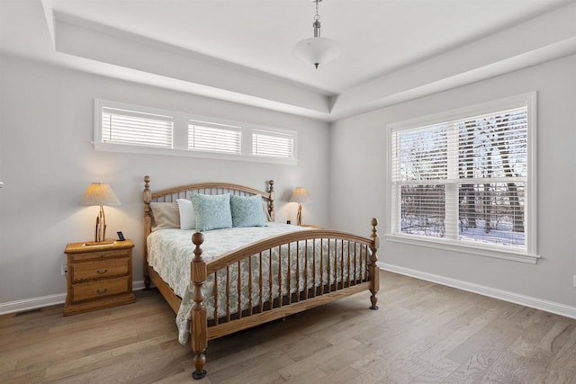 bedroom with light wood-type flooring, multiple windows, and baseboards