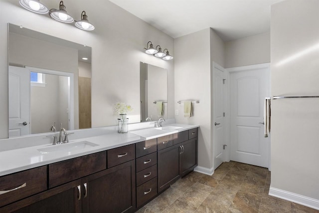 full bath featuring double vanity, baseboards, and a sink