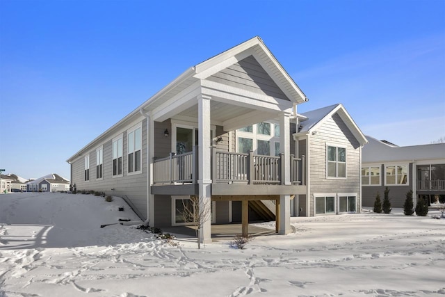 snow covered back of property with stairway and a garage