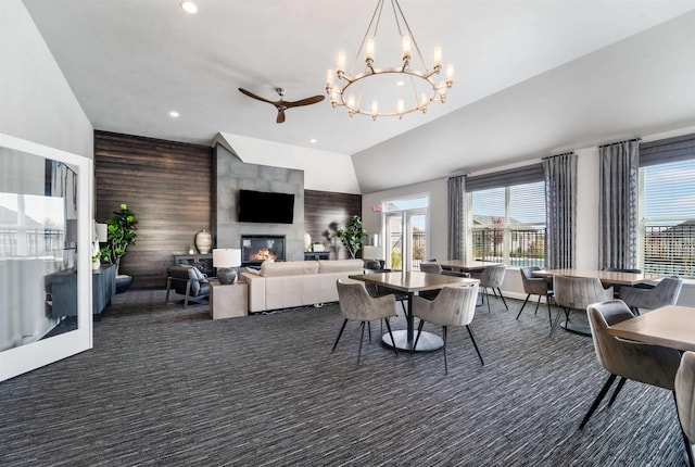 carpeted dining area featuring a ceiling fan, recessed lighting, wood walls, a fireplace, and an accent wall