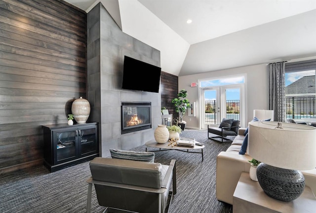 living room with a tiled fireplace, vaulted ceiling, and carpet floors