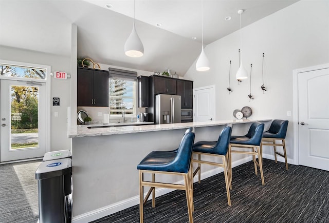 kitchen featuring a peninsula, a breakfast bar area, light stone countertops, and stainless steel refrigerator with ice dispenser