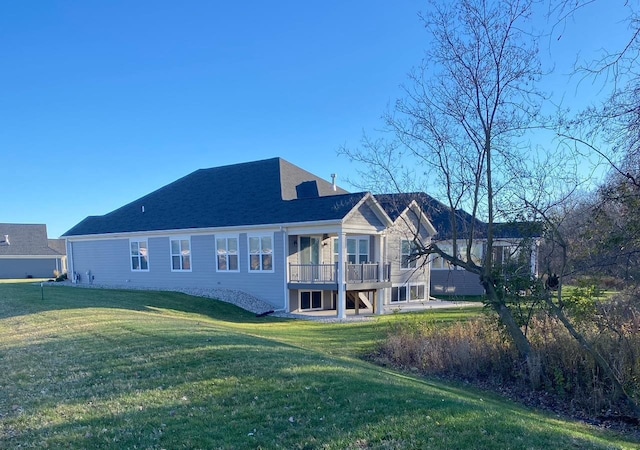 back of property with a deck, a lawn, and roof with shingles