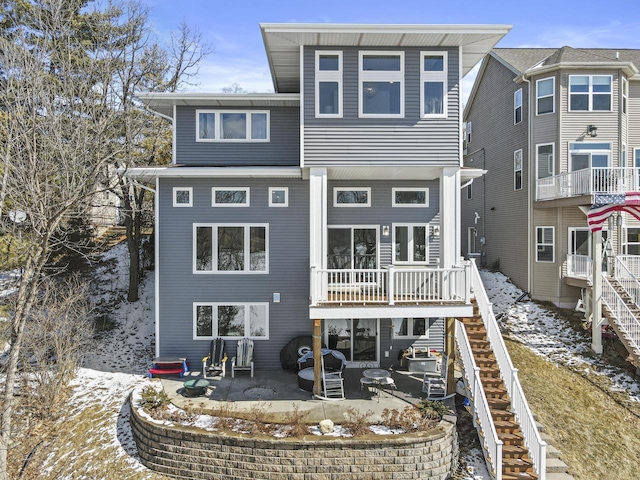 snow covered property with stairway and a patio