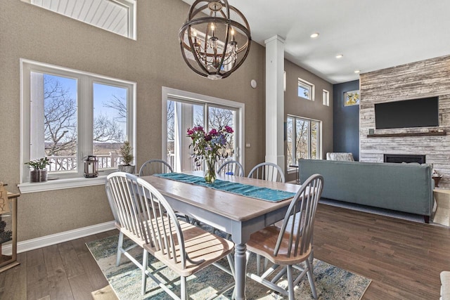 dining room featuring baseboards, recessed lighting, a fireplace, an inviting chandelier, and wood finished floors