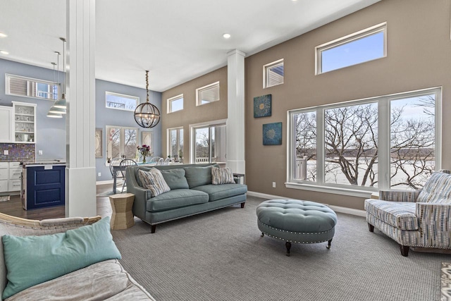 carpeted living area featuring a high ceiling, a notable chandelier, recessed lighting, and baseboards