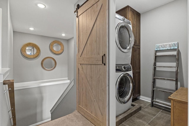 laundry area featuring a barn door, recessed lighting, and stacked washing maching and dryer