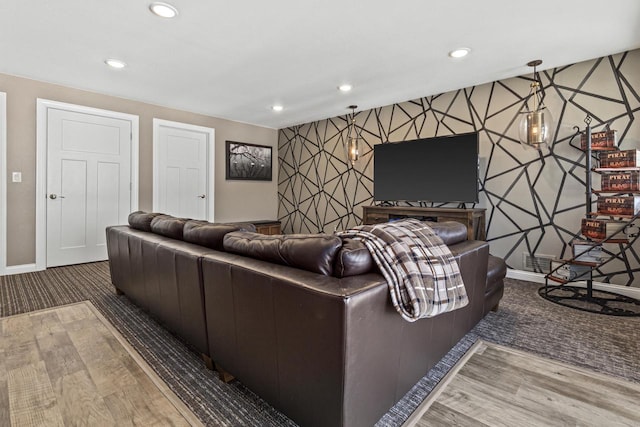 living area with wood finished floors, an accent wall, and wallpapered walls