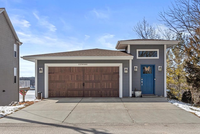 view of front of house with an attached garage, driveway, and a shingled roof