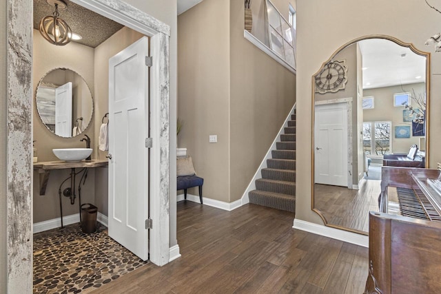 foyer with baseboards, stairs, a high ceiling, wood finished floors, and arched walkways