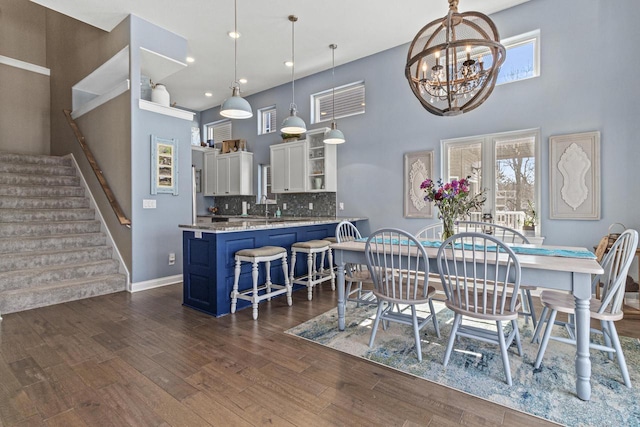 dining area featuring a wealth of natural light, stairway, a towering ceiling, and dark wood-style flooring