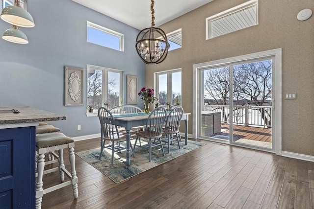 dining area with baseboards, an inviting chandelier, dark wood-style flooring, french doors, and a towering ceiling