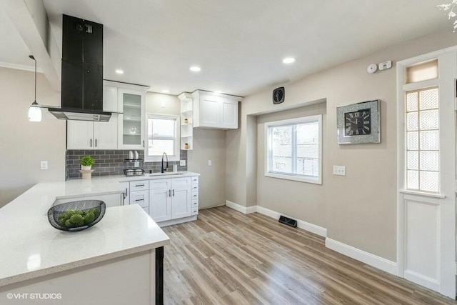 kitchen with a sink, decorative backsplash, light wood-style flooring, and island range hood