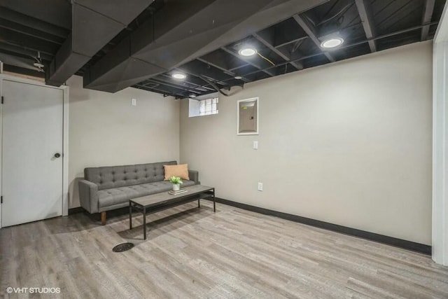 living area featuring electric panel, baseboards, and wood finished floors