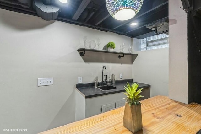 kitchen featuring dark countertops, open shelves, and a sink