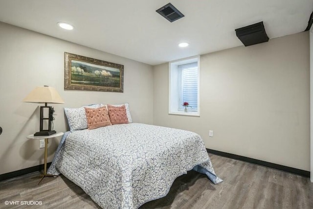 bedroom with wood finished floors, visible vents, and baseboards