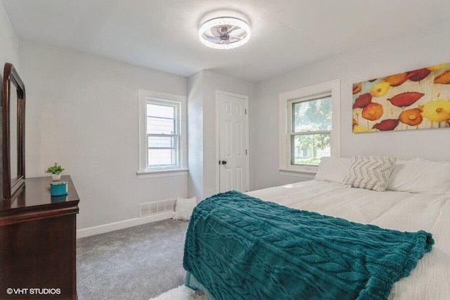 carpeted bedroom with visible vents, multiple windows, and baseboards