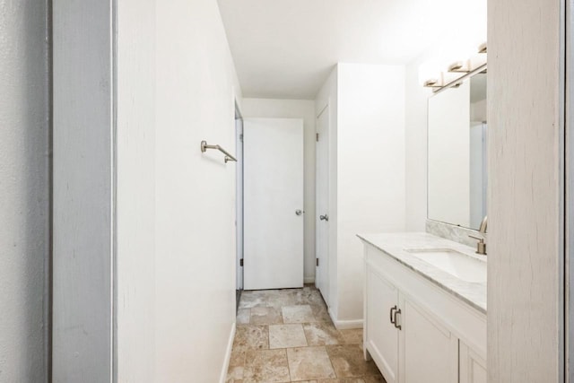 bathroom with baseboards, vanity, and stone finish floor