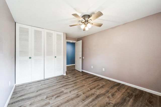 unfurnished bedroom featuring a ceiling fan, wood finished floors, a closet, and baseboards