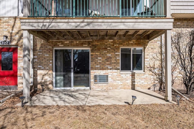 property entrance with brick siding, a balcony, and a patio