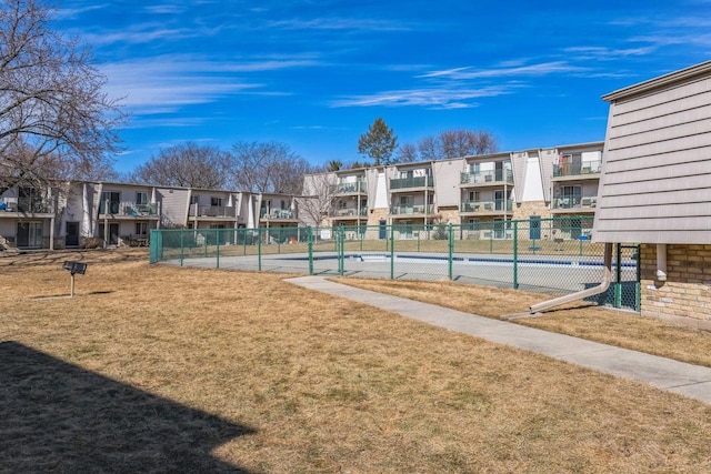 view of community featuring a residential view, a lawn, and fence