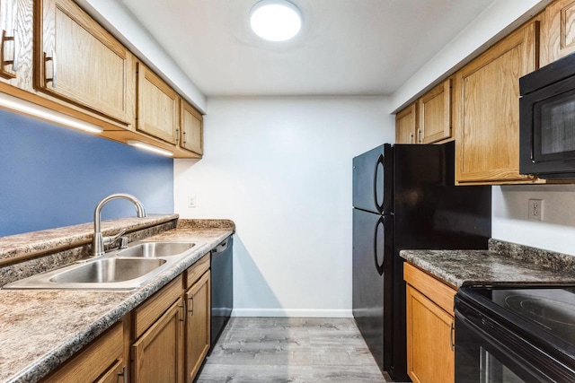 kitchen with light wood finished floors, baseboards, brown cabinets, black appliances, and a sink