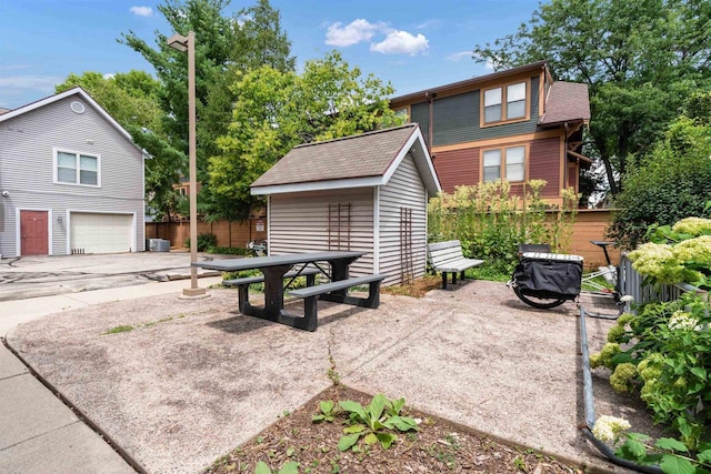 view of patio / terrace featuring a garage, central AC, an outdoor structure, and fence