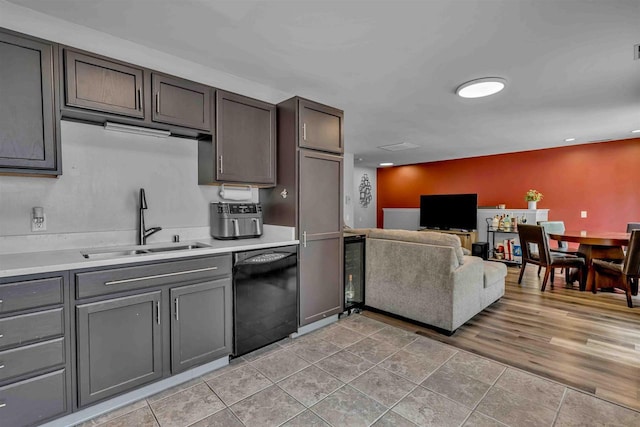 kitchen with light countertops, black dishwasher, open floor plan, and a sink