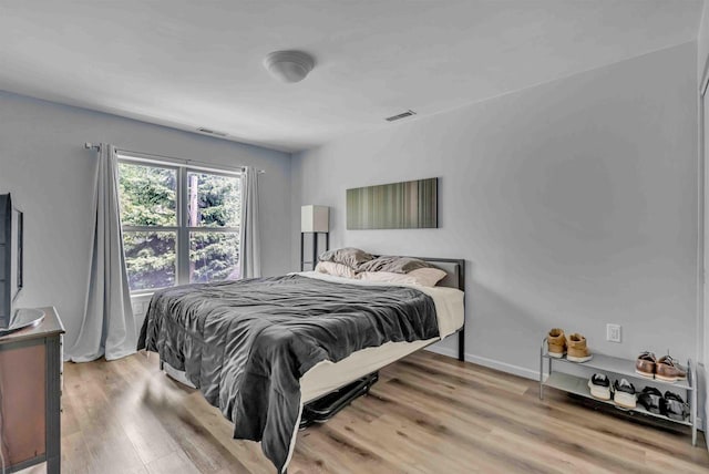 bedroom with wood finished floors, visible vents, and baseboards