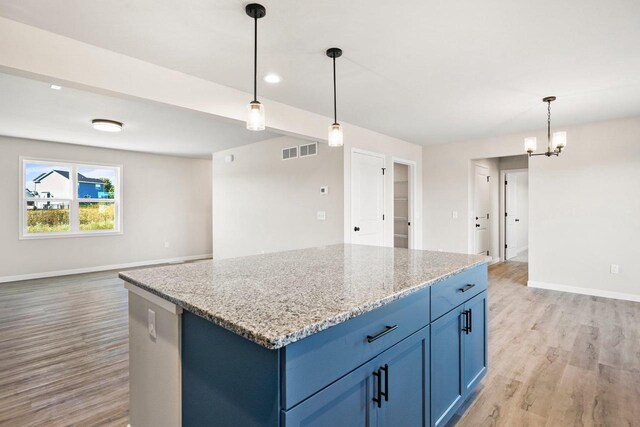 kitchen featuring baseboards, visible vents, light wood-style flooring, blue cabinets, and a center island