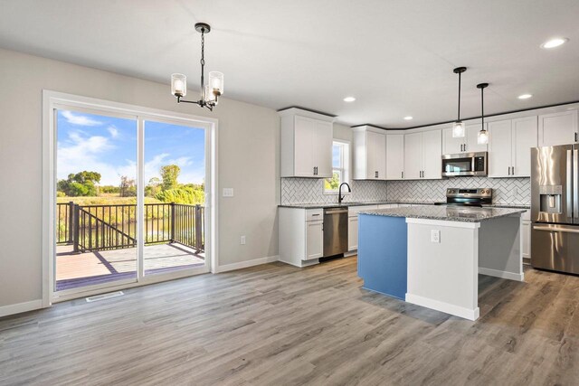 kitchen with a kitchen island, backsplash, stainless steel appliances, and light wood-style floors