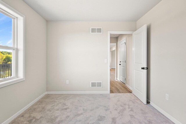 carpeted empty room with visible vents and baseboards