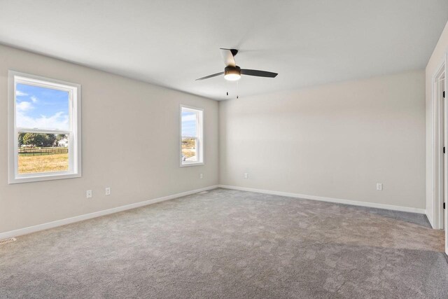 unfurnished room with visible vents, baseboards, a ceiling fan, and carpet flooring