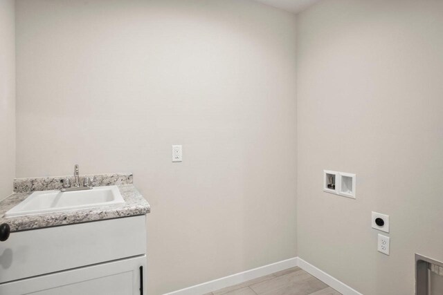 laundry room with baseboards, hookup for an electric dryer, cabinet space, a sink, and washer hookup