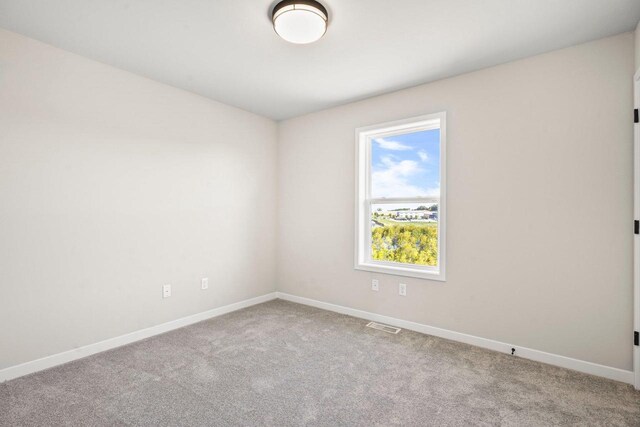 carpeted spare room featuring baseboards and visible vents