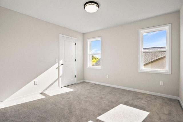 carpeted empty room featuring baseboards