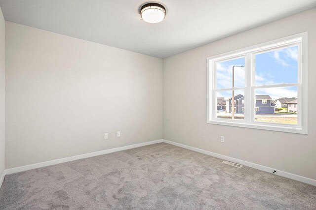 empty room featuring carpet flooring, baseboards, and visible vents